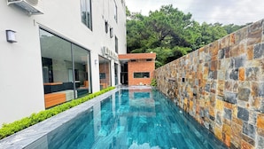 Un bâtiment moderne doté d’une piscine, de portes vitrées et d’un mur en pierre.