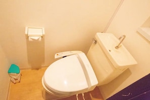 A small bathroom with a toilet, sink, and a toilet paper holder on the wall. - Shirakabanoyado-Akinai (Osaka)