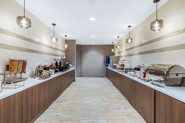 Una cocina moderna con una encimera larga, equipada con electrodomésticos y alimentos diversos.