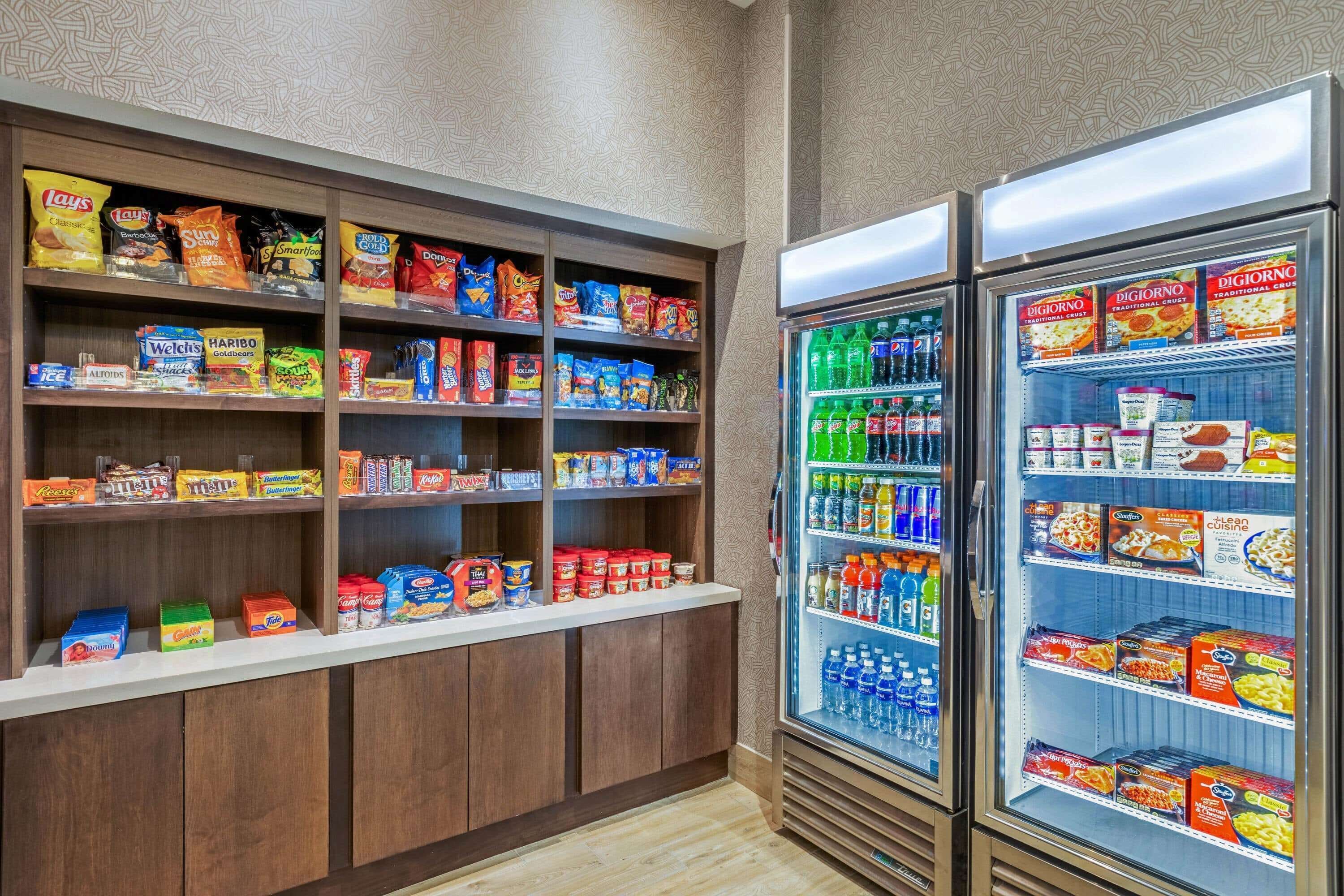 Un área de exhibición de bocadillos y bebidas, con estantes llenos de diferentes opciones y una sección refrigerada para bebidas.
