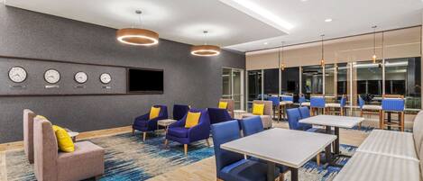 A hotel lobby with seating areas, tables, and a wall-mounted clock.