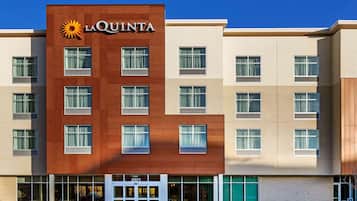 A La Quinta hotel building with a modern design, featuring a mix of brick and beige facades, large windows, and a prominent entrance.