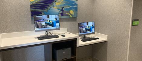 A workspace with two computer monitors, a keyboard, and a mouse on a white desk against a patterned wall.
