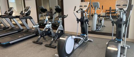 A gym with various exercise machines, including treadmills, stationary bikes, and elliptical trainers.