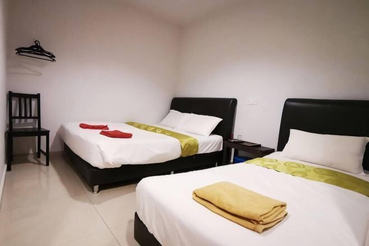 Quarto de hotel com duas camas, uma cadeira e uma mesa de cabeceira.
