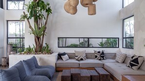 Uma sala de estar moderna com sofá seccional, mesa de centro e janelas amplas.
