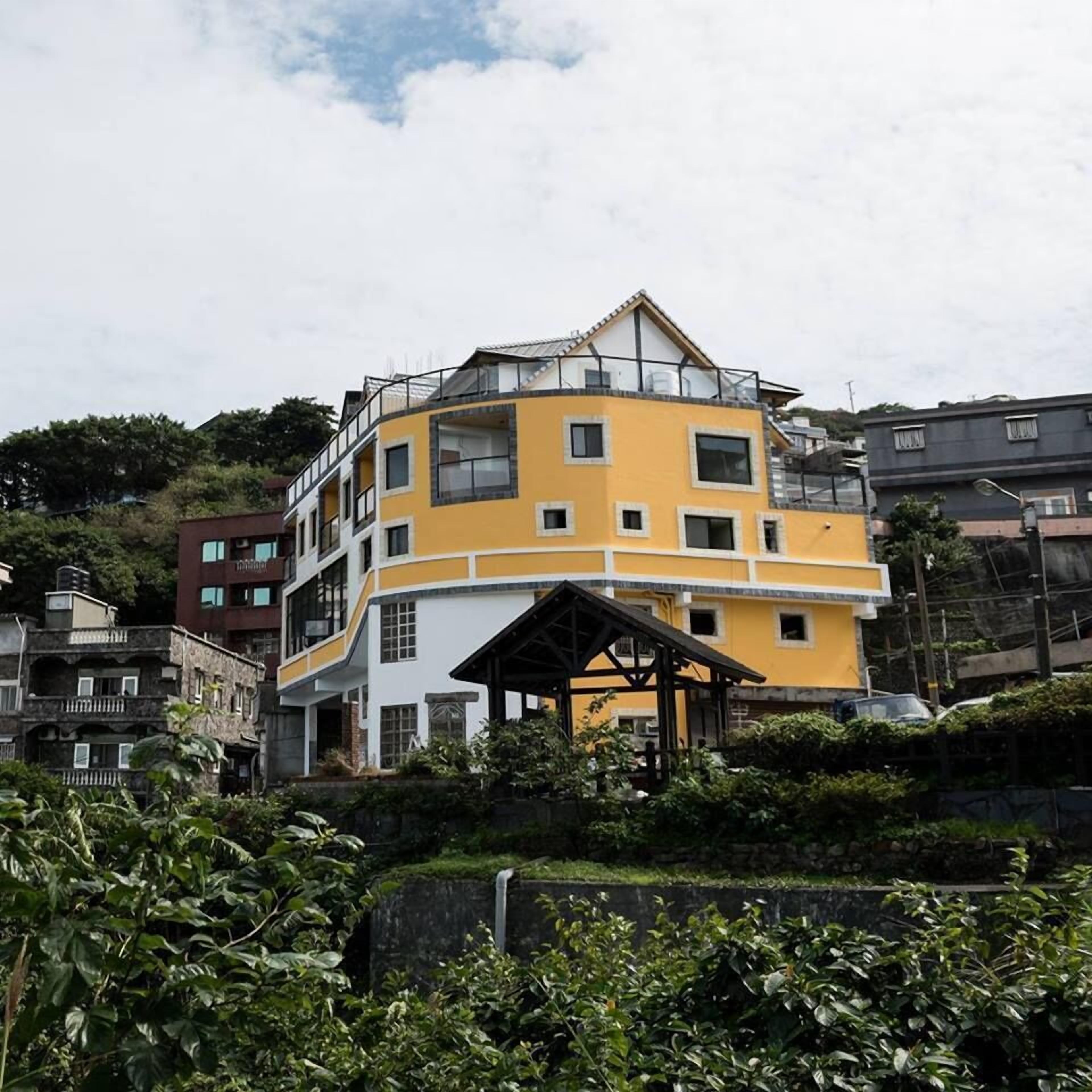 A multi-story building with a yellow facade, multiple windows, and a balcony.