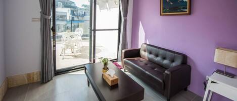 A living room with a sofa, a coffee table, and a painting on the wall.
