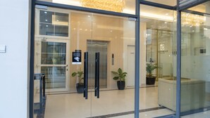 L’entrée d’un hôtel moderne, avec une porte en verre, un comptoir d’accueil et un lustre.