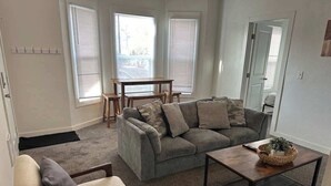 Ein Wohnzimmer mit grauem Sofa, einem Holztisch und einem beigen Sessel.