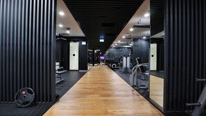 A gym with wooden flooring, mirrored walls, and various exercise equipment. - FV By Serain Residences (Fortitude Valley)