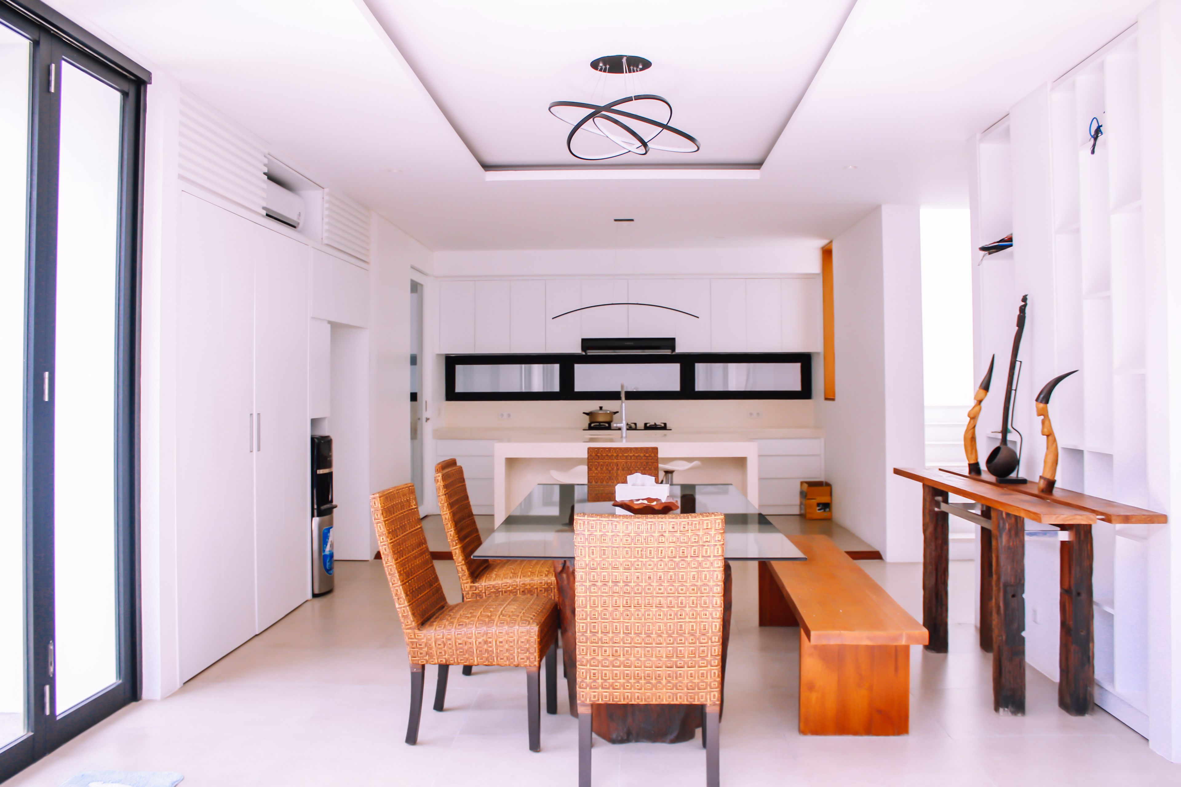 A modern dining area with a glass-top table, wooden chairs, and a wooden bench.