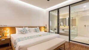 A modern bedroom with a large bed, bedside tables, a bench, a glass-enclosed shower, and a visible bathroom. - Villa Damar Canggu by Nagisa Bali (Canggu)