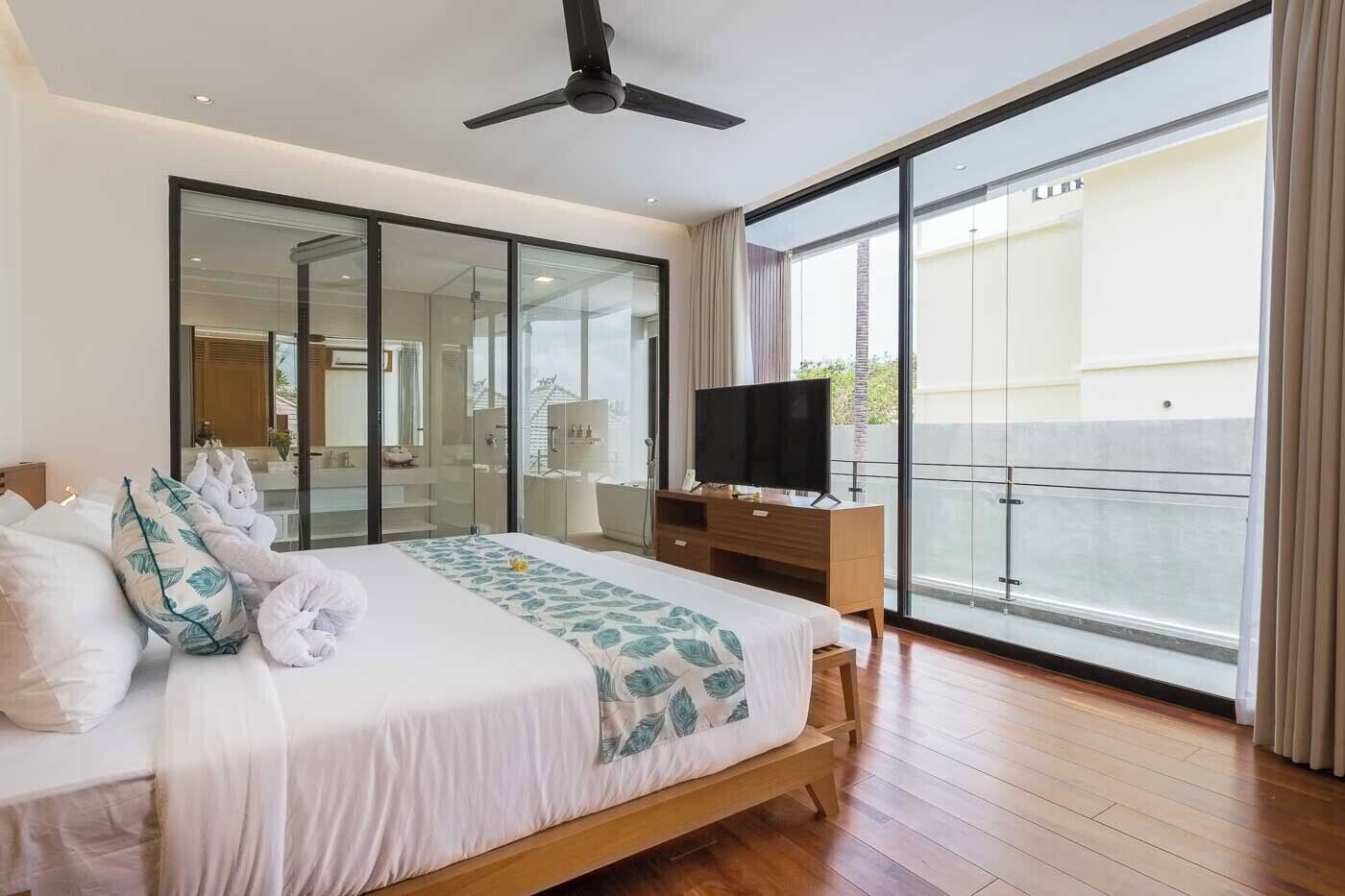 Quarto moderno com cama grande, televisão e varanda com vista.