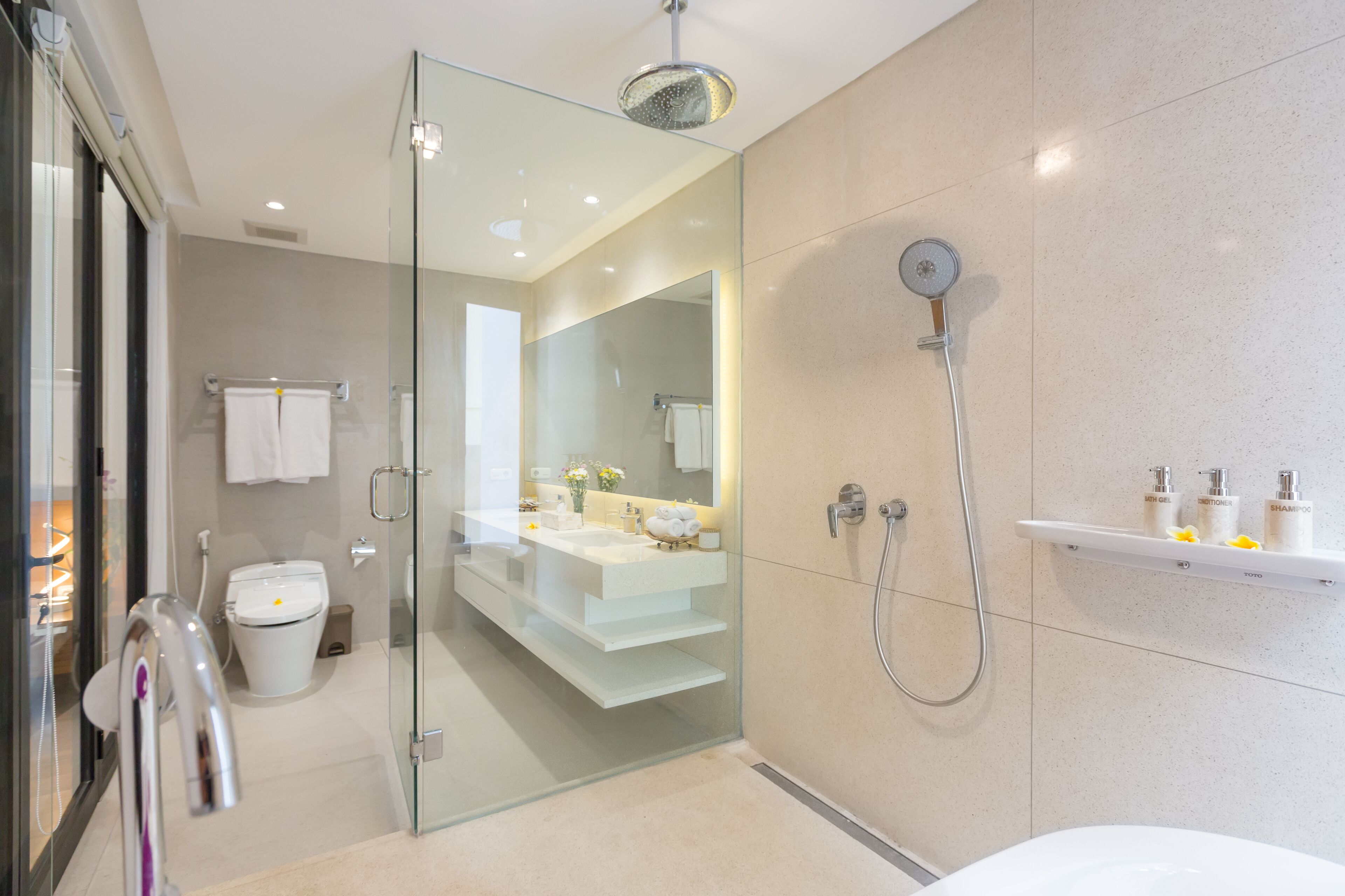 A modern bathroom with a glass shower enclosure, a white sink, and a toilet.