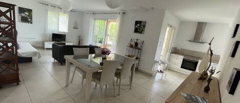 A spacious living area with a dining table, sofa, and kitchen.
