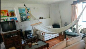 Una sala de estar con una hamaca, un sofá, un televisor y una mesa de centro.