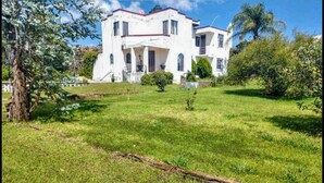 Un edificio blanco con techo rojo, rodeado de césped cuidado y árboles.