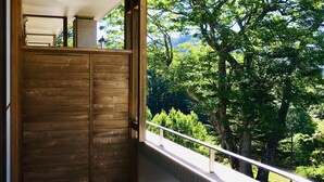 A wooden door leading to a balcony with a view of lush green trees and a mountain in the background. - Lake Side Nikko Hotel (Nikko)