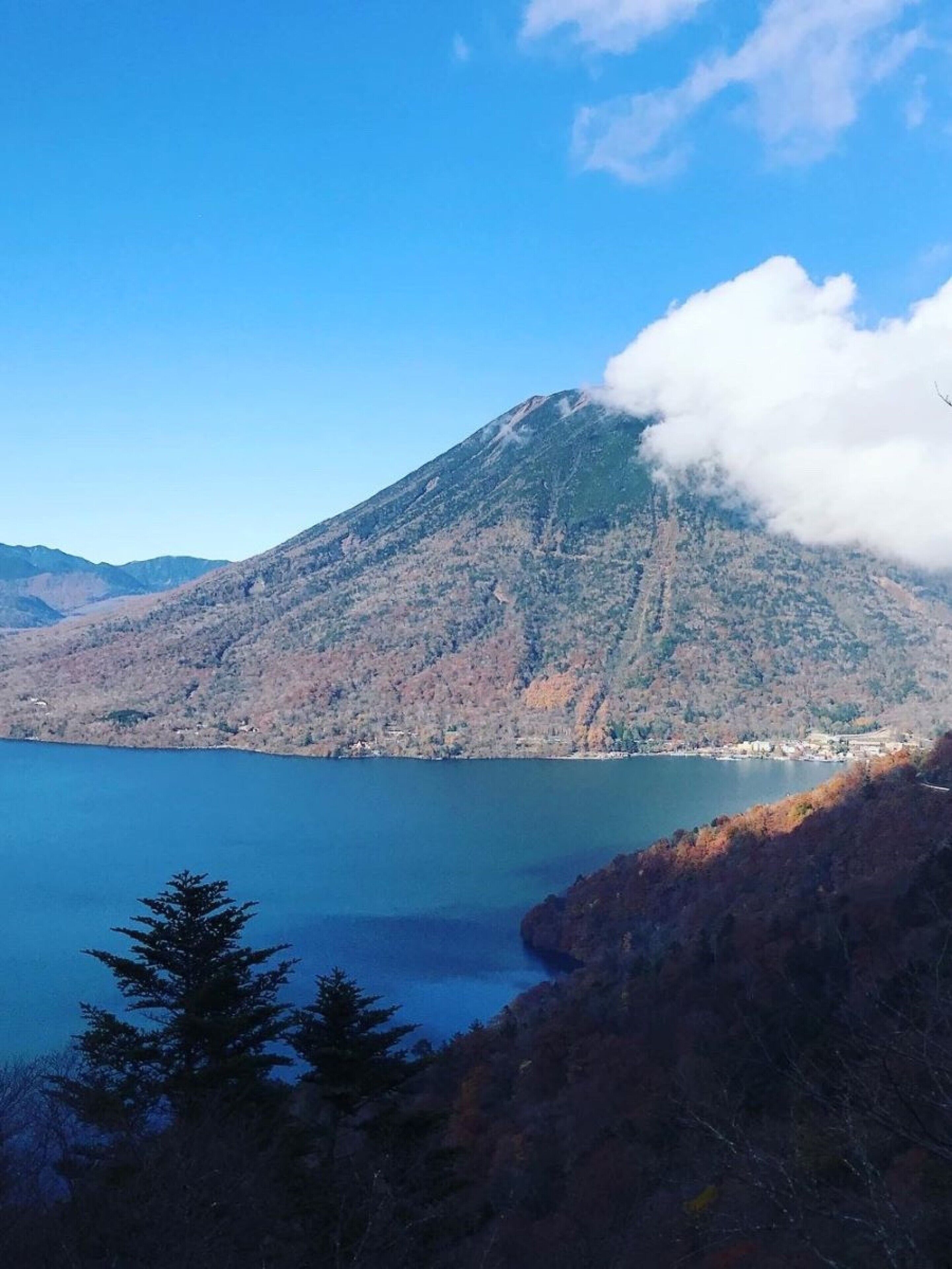 A mountain with a lake in the foreground and a small settlement at its base.