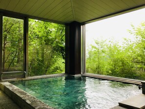 Una piscina con agua cristalina, rodeada de amplios ventanales que ofrecen vistas de un follaje exuberante.