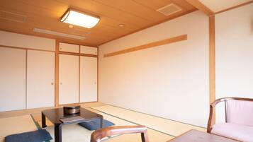 A traditional Japanese room with tatami flooring, a low table with a bowl, a cushioned chair, and sliding doors.