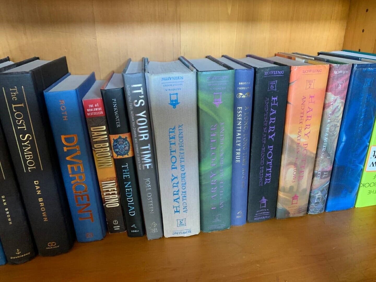 Una estantería con una variedad de libros, incluyendo títulos como 'The Lost Symbol' y 'Divergent'.