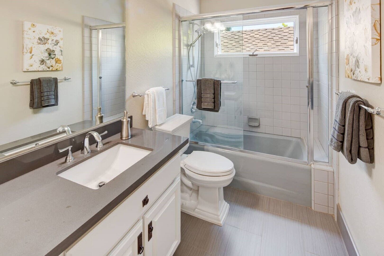 Une salle de bain moderne avec un grand miroir, un lavabo, des toilettes et une douche à parois de verre.
