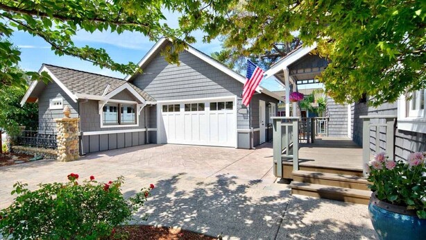A residential house with a garage, a stone pillar, and a flag.