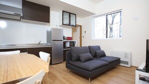 Ein zeitgemäßer Wohnbereich mit Essbereich, Küchenzeile und einem grauen Sofa.