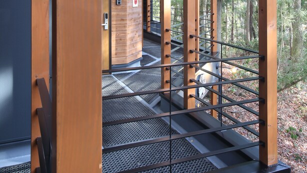 Eine Holzkonstruktion mit Metalltreppe und Blick auf einen Wald.