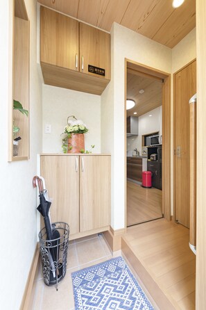 A compact kitchen with wooden cabinets, a microwave, and a red trash bin.