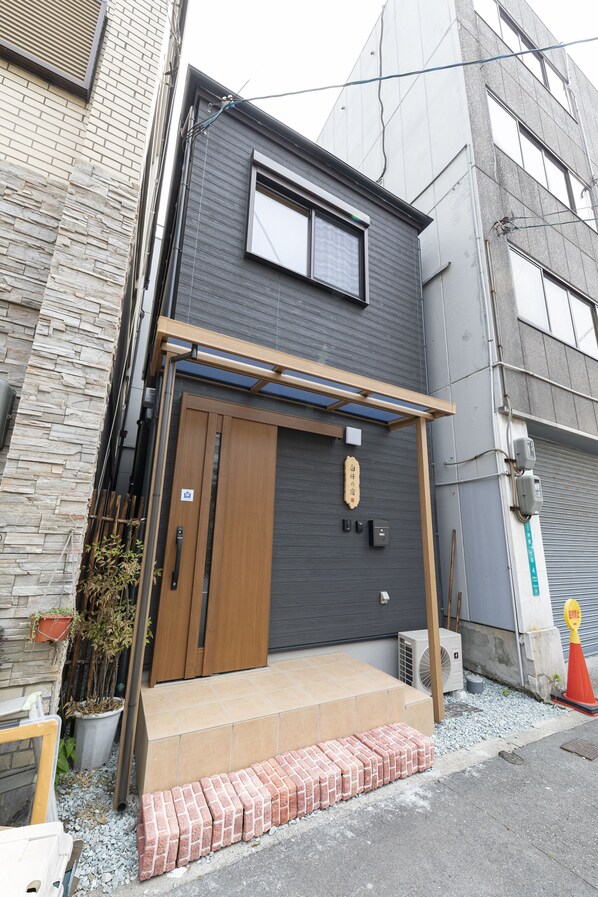 A modern building with a wooden door, a small porch, and a potted plant.