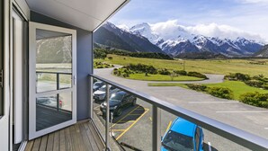 Een balkon met uitzicht op een parkeerterrein en bergen.