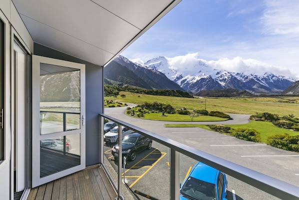 A balcony with a view of a parking area and mountains.
