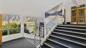 Een trap die leidt naar een kamer met uitzicht op een berg, te zien door grote ramen.