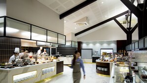 Een moderne keuken met marmeren vloeren, roestvrijstalen apparatuur en een buffetgedeelte met diverse gerechten.