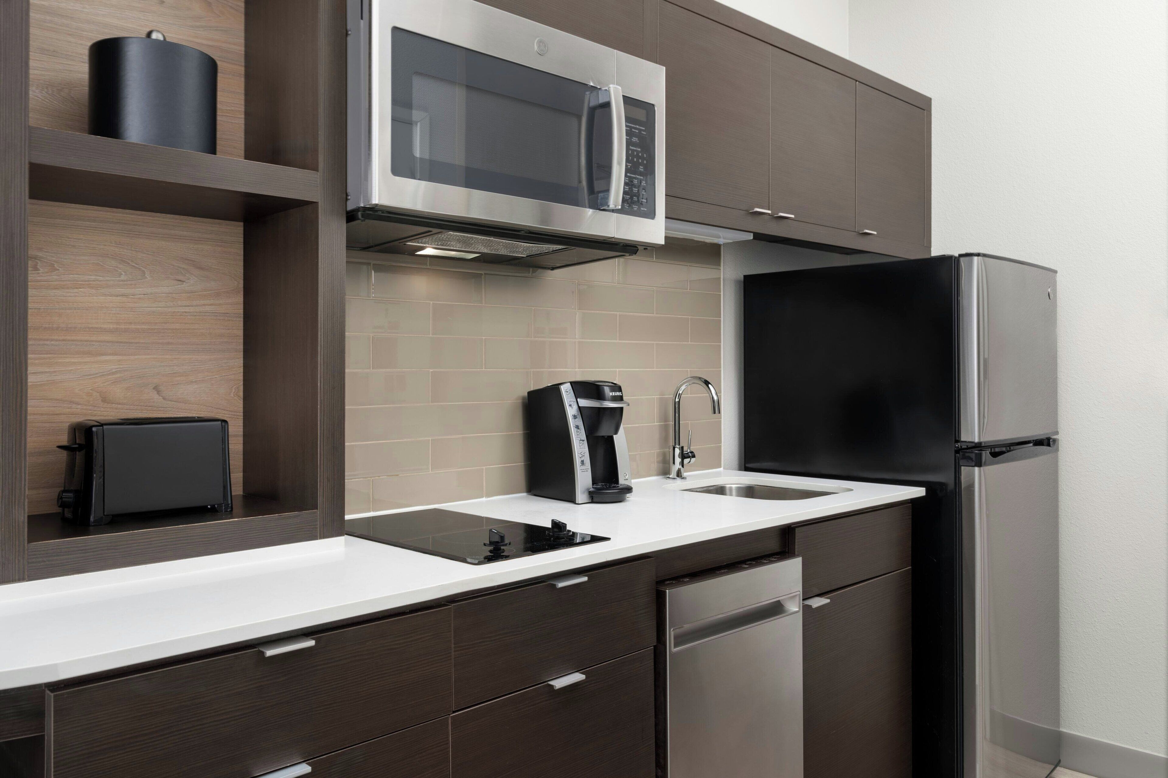 A modern kitchen with a built-in microwave, coffee maker, and dishwasher.