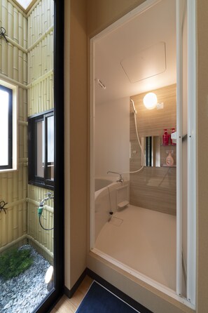 A bathroom with a bathtub, a window, and a shower. - Shirakabanoyado-Siokusa (Osaka)