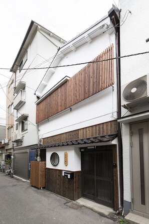 A two-story building with a wooden shoji screen, a black gate, and a small round window. - Shirakabanoyado-Siokusa (Osaka)