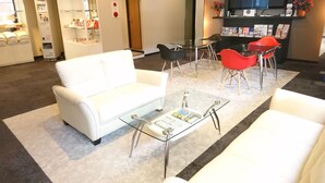 Eine moderne Hotelhalle mit einem weißen Sofa, einem Glastisch und einer Rezeption mit Zeitschriften.