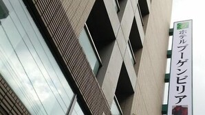 Ein modernes Gebäude mit einem auffälligen Zickzack-Muster an der Fassade und einem Schild mit japanischen Schriftzeichen.