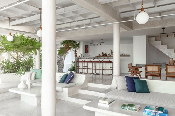Un intérieur moderne aux couleurs claires, comprenant un canapé, une table basse et un escalier.