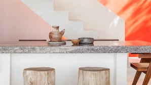 Eine Küche mit Granitabdeckung, einer rustikalen Vase und einem Holzhocker.