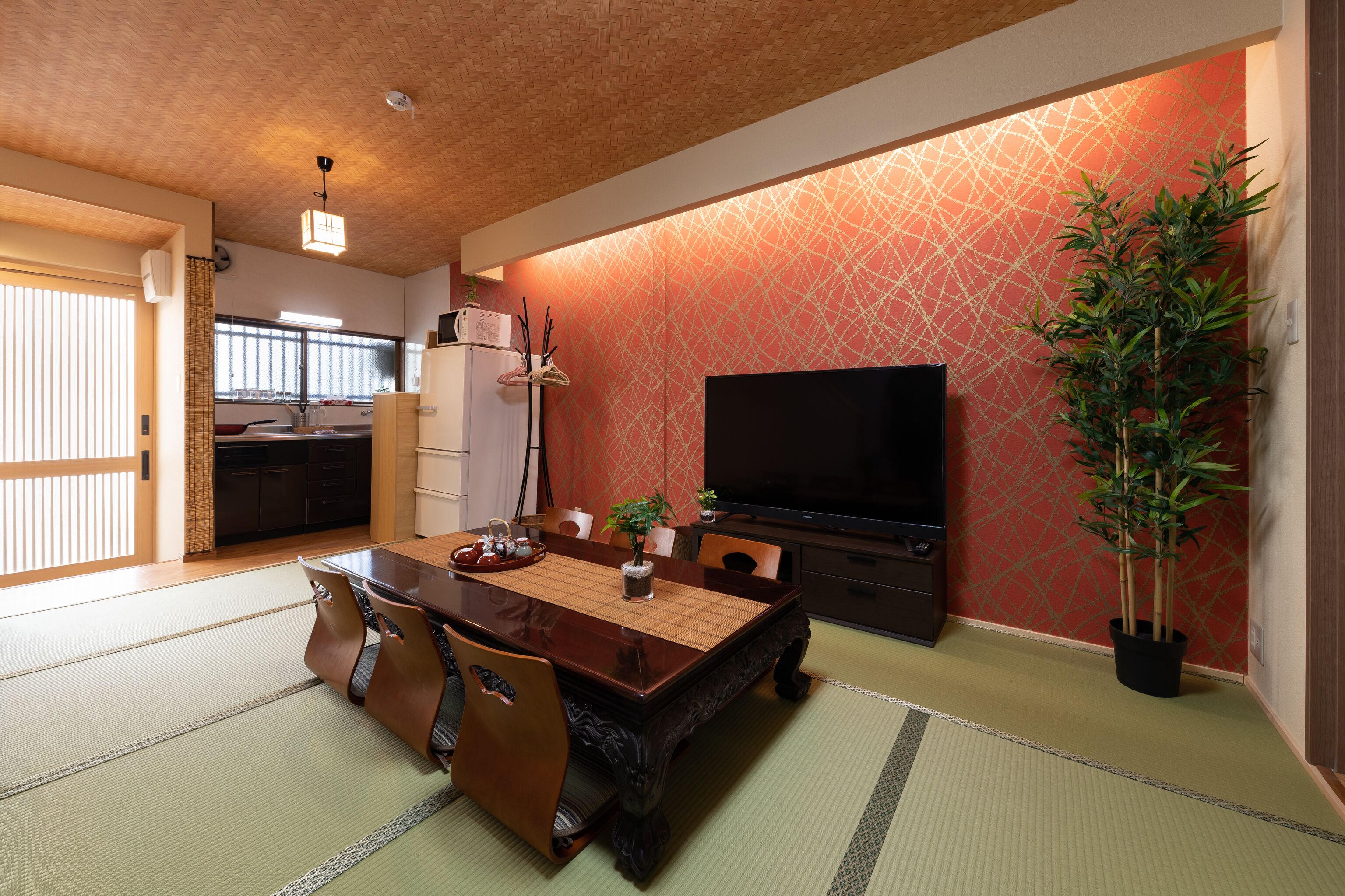 A traditional Japanese-style dining room with tatami flooring, a low table, and a television.