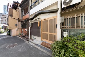 A traditional Japanese house with a sliding wooden door, a small front garden, and a street view. - Shirakabanoyado-Tennoji (Osaka)