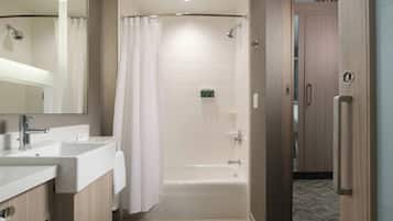 A modern bathroom with a bathtub, a shower, and a vanity with a mirror.