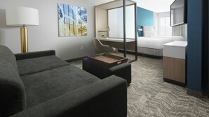 A modern hotel room with a sofa, a desk, a bed, and a large mirror. - SpringHill Suites by Marriott Texas City (Texas City)