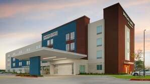 A modern hotel with a blue and brown facade, a covered parking area, and a sign for SpringHill Suites by Marriott. - SpringHill Suites by Marriott Texas City (Texas City)