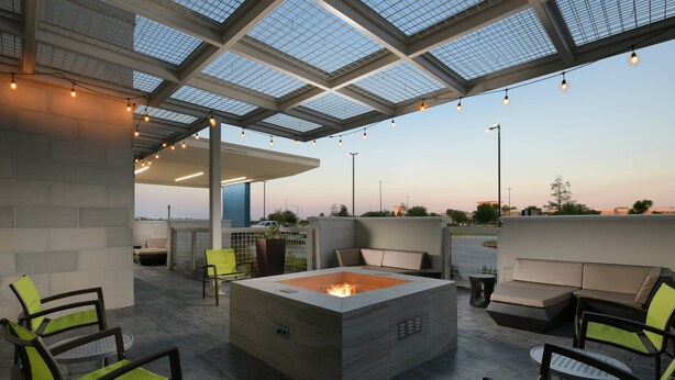 An outdoor seating area with a fire pit, chairs, and a modern architectural design. - SpringHill Suites by Marriott Texas City (Texas City)
